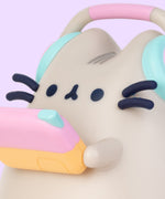 Close-up view of Gaming Lamp. The plastic lamp features Pusheen’s whiskers and paws as well as headphones and a gaming device that extend off the plastic body.  