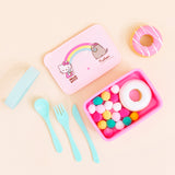 Top view of the a pink lunchbox with it’s lid placed above it, a teal knife, fork, spoon and rubber band placed neatly to the left. The lunch box lid features Hello Kitty holding a donut on the left with the text ‘Hello Kitty’ underneath her, Pusheen wearing a hair bow and holding a donut on the right with the text ‘Pusheen’ underneath, and a rainbow in the middle connecting the two with a small pink heart underneath it. Multicolor pom poms and a white glazed donut are inside the box.