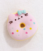 Full front view of Pusheen the Cat side of the reversisble Donut Plush. The strawberry glazed plush toy lays on a light white carpet surface.  