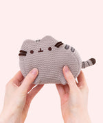 Back view of Knit Pusheen Plush. In this view, the front whiskers can be seen extending off the front of the plush. The plush sits atop little, crocheted paws. 