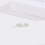 Front view of sterling silver finish of Lazy Stud Earrings. The earrings are an unmatched pair of Pusheen sitting in two different loaf poses. 