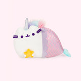 A white Pusheen with a pink mermaid tail with a purple scallop rim and reflective green scales and a green fin, sitting on her side while holding a star in her paws. Mermaid Pusheenicorn has sea green head stripes, a unicorn horn, and a purple, green and pink fluffy mane that ends right as her mermaid tail begins. 