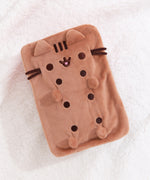 Top view of the squisheen plush shows off Pusheen’s brown face and four paws. Pusheen plush lies on a white surface.  