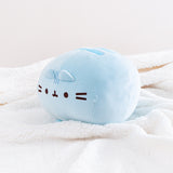 The Blue Round Squisheen Plush sitting alone in a quarter profile in a sea of a fluffy white blanket, a singular, perfect blue orb.