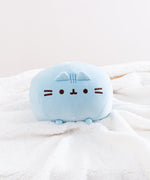 Front view of the Blue Round Squisheen sitting on top a fluffy white blanket. She is angled upwards so her feet emerge out.