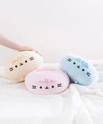The Round Squisheen Plush trio collapsed on top of a fluffy white blanket, a model’s hand emerging from the left to rest on top of the yellow plush, the pink plush hiding her feet in the middle, and the blue plush on the right nearly on it’s side.