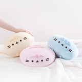 The Round Squisheen Plush trio collapsed on top of a fluffy white blanket, a model’s hand emerging from the left to rest on top of the yellow plush, the pink plush hiding her feet in the middle, and the blue plush on the right nearly on it’s side.
