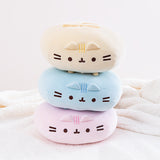 The three Round Squisheen Plush stacked on top of one another, facing the camera and sitting on top a white fluffy blanket. The pink plush is at the bottom, blue in the middle, and yellow on the top. The pink and blue plush are squished down enough to look as if they have no feet, but the yellow round Pusheen still has her feet.