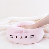 A model’s hand pressing down on the Pink Round Squisheen, demonstrating the plush’s squishiness. 