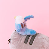 Back Quarter view close up of the Bo and Pusheen plush. Bo's back features five light grey stripes on her back, and a light blue tail that reaches out to the second stripe on Pusheen's back. Bo's tail is rounded off.