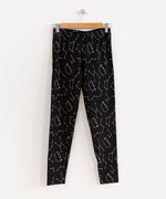 The Pusheen Celestial Leggings hanging from a wooden hanger in front of a white background.