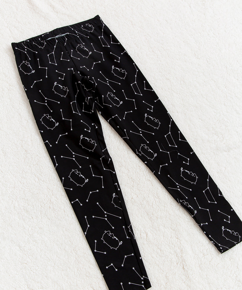 Top view of the Celestial leggings, laying flat at an angle on top of a fuzzy white blanket. The pattern on the leggings continues up to the elastic waistband. Some of the constellations in the legging pattern includes the Big Dipper.