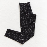 The Pusheen Celestial Leggings partially folded in half, on top of a white fuzzy blanket.