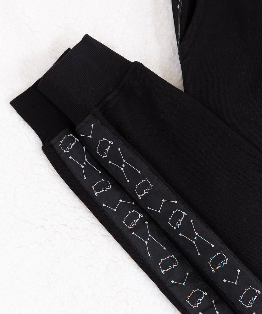 Front view of the Pusheen Celestial Jogger, hanging from a white clothes hanger in front of a white background. The pattern on the side is not visible from the front, making the item appear like a solid black jogger.