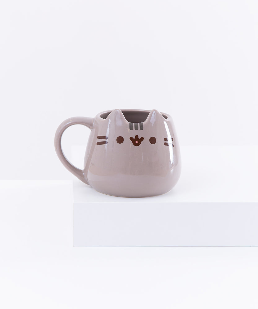 The Pusheen Character Mug resting on top of a white pedestal in front of a white background.