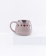 The Pusheen Character Mug resting on top of a white pedestal in front of a white background.
