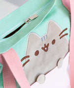Close-up view of the zipper-closure and Pusheen applique. The tote bag closes shut. The applique of Pusheen is grey velour.  