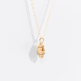 A close-up view of the side of the Pusheen Dipped Cone Necklace in Gold Vermeil. Pusheen the Cat’s classic face and whiskers have been included in the dipped ice cream cone charm. 