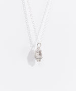 Sterling silver finish of Pusheen Dipped Cone Charm Necklace in its white packaging box. The necklace is hanging inside the white box with a pink, white, and purple informational card. 
