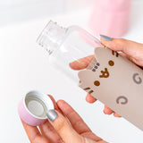 Close-up view of model holding glass water bottle. Model holds the lid of the water bottle to show the inside mechanism that seals the water bottle when closed.  