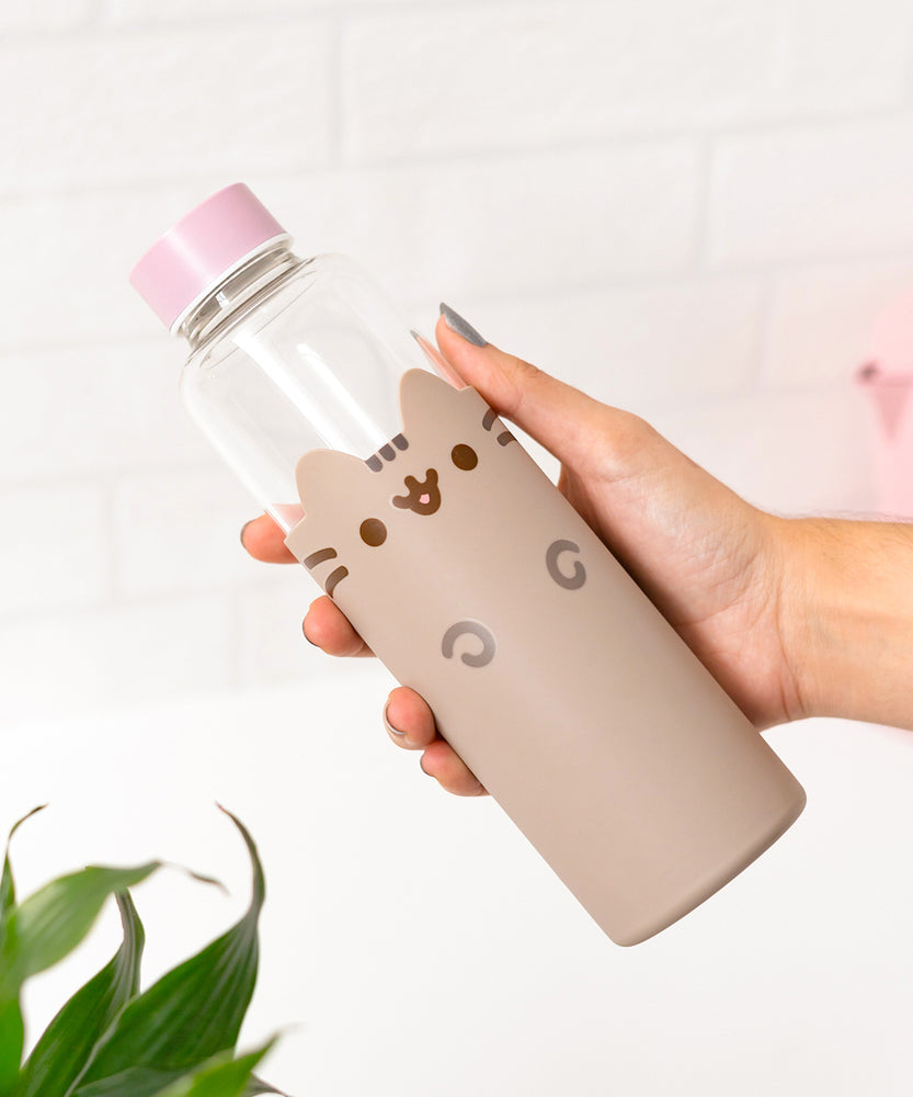 Model holds water bottle to show size of glass bottle with pink top and grey silicone sleeve. 