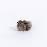 Full view of the mini skunk plush from the collectors set. The skunk resembles Pusheen, but with dark grey fur and a fluffy black tail with a stripe of white felt on top.