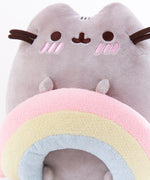 Back view of the Pushen with Rainbow Plush in front of a white background. Pusheen’s back has the standard two back stripes and a striped tail. Pusheen’s whiskers and rainbow stick out partially from the other side. The information tag for the plush is located to the left of the tail.