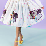 Full view of front of the Pusheenicorn Magical Jewel Skirt worn by a model who is wearing yellow shoes and standing in front of a light purple background. The skirt is held out to one side so the skirt falls away from the body to show off the repeating print pattern. 