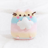 The Rainbow Pusheen Plush sitting upright in a fuzzy white space, matching the cloud Pusheen is holding.