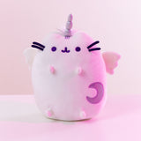 The Super Pusheencorn plush in front of a white background, bathed in a magenta light. The Super Pusheenicorn plush reflects the light around her and appears light pink as a result.