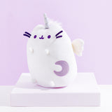 Quarter view of the Super Pusheenicorn Plush facing the left on top of a white square pedestal, in front of a light purple background.