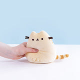 A model’s hand squeezing the Yellow Mini Squisheen Plush, demonstrating it’s squishiness.