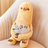 Sloth holding a mini Pusheen plush, sitting in a big beige armchair. Sloth is a golden brown rounded rectangle with long arms and legs that have three brown claws each. Sloth’s arms are long enough to hold a mini Pusheen in his lap. Sloth’s fur is lightly fuzzy, and his face features a round snoot with a brown dot nose, and two dot eyes with light brown rings around them. 